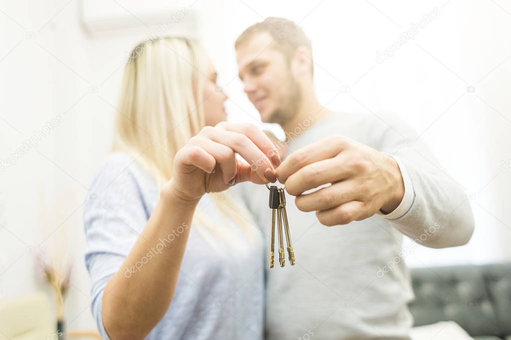 A lovely young couple holds in front of them the keys to their new apartment.