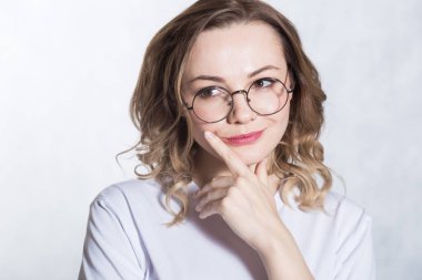 Gözlük ile gülümseyen güzel genç kadın çenesini tutan, etrafına bakarak, bir karar yapmaya çalışır.