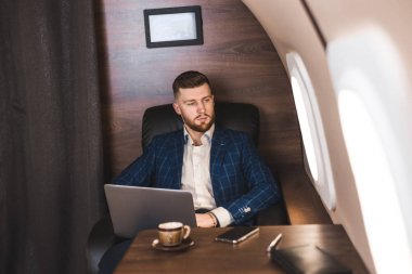 Onun özel jet bir sandalyede otururken bir laptop üzerinde çalışan çekici ve başarılı işadamı.