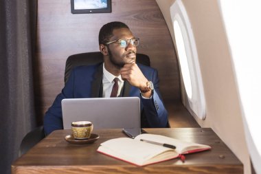 Onun özel jet sandalyede otururken gözlük bir dizüstü bilgisayar üzerinde çalışan çekici ve başarılı Afrikalı Amerikan işadamı.