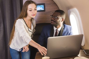 Genç başarılı Afrikalı-Amerikan işadamı gözlük ve çekici bir kadın iş arkadaşı Sarışın özel bir Jet. Hizmet ve uçuş birinci sınıf