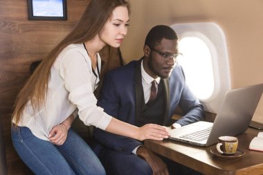 Genç başarılı Afrikalı-Amerikan işadamı gözlük ve çekici bir kadın iş arkadaşı Sarışın özel bir Jet. Hizmet ve uçuş birinci sınıf