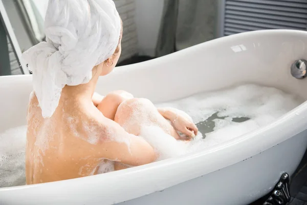 Una giovane ragazza attraente si rilassa in bagno e riposa sullo sfondo di un bellissimo interno leggero. Trattamenti Spa per la bellezza e la salute con la cura della pelle — Foto Stock