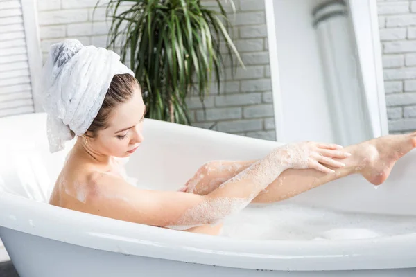 Una giovane ragazza attraente si rilassa in bagno e riposa sullo sfondo di un bellissimo interno leggero. Trattamenti Spa per la bellezza e la salute con la cura della pelle — Foto Stock