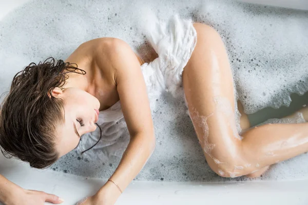 Una giovane ragazza attraente si rilassa in bagno e riposa sullo sfondo di un bellissimo interno leggero. Trattamenti Spa per la bellezza e la salute con la cura della pelle — Foto Stock