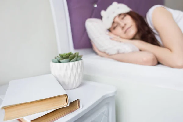 An attractive young brunette girl woman sleeps in her bed in a sleep mask