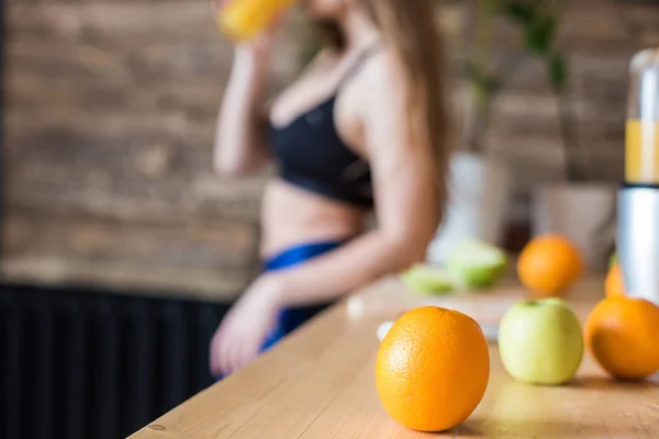 Vonzó lány sportruházat készít egy egészséges reggeli edzés előtt a konyhában, vágja gyümölcs és italok friss gyümölcslé készült gyümölcsfacsaró. Az egészséges táplálkozás, fitnesz és szépség előnyei — Stock Fotó