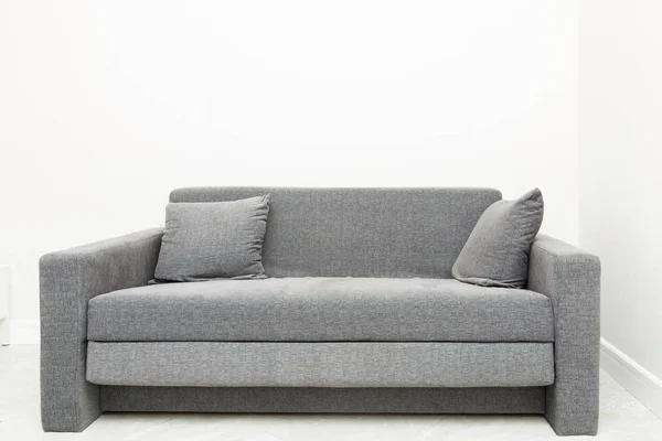 Klasický moderní šedý gauč s polštáři ve světlém interiéru bytu — Stock fotografie