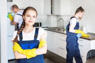 İş sırasında profesyonel ekipmanlarla temizlik hizmeti. Profesyonel mutfak temizliği, kanepe kuru temizleme, pencere ve yer silme. Erkek ve kadın üniformalı, tulumlu ve lastik eldivenli.