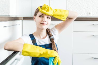 İş sırasında profesyonel ekipmanlarla temizlik hizmeti. Profesyonel mutfak temizliği, kanepe kuru temizleme, pencere ve yer silme. Erkek ve kadın üniformalı, tulumlu ve lastik eldivenli.