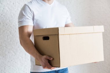 Bir daireye taşınmak için karton kutuları yükleyen güçlü, kaslı bir adam. Profesyonel ulaşım işçisi, tulumlu erkek yükleyiciler. Metin için boş alan, izole edilmiş