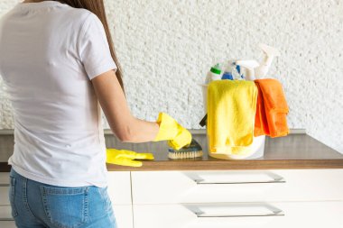 Profesyonel ev temizliği. Genç bir kadın daireyi temizliyor. Yakın plan, paçavra, sünger ve kova, malzeme personeli..