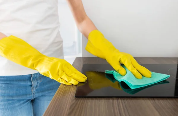 Seorang wanita muda dari perusahaan pembersih profesional membersihkan rumah. Seorang pria mencuci dapur dengan sarung tangan kuning dengan peralatan pembersih. — Stok Foto