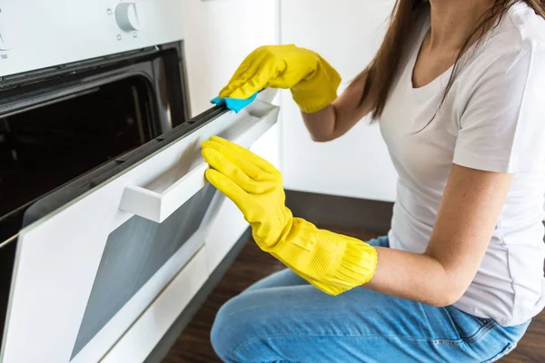 A young woman from a professional cleaning company cleans up at home. A man washes the kitchen in yellow gloves with cleaning supplies stuff. — Stock Photo, Image