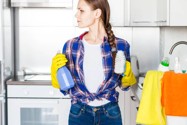 Uma jovem faz a limpeza em casa, lava a cozinha. Balde com trapos e luvas amarelas na mesa — Fotografia de Stock