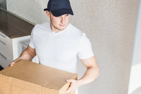 Delivery strong, muscular man loading cardboard boxes for moving to an apartment. professional worker of transportation, male loaders in overalls. free space for text, isolated