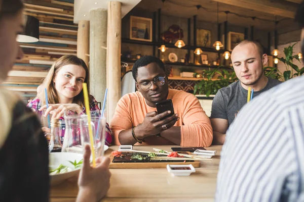 Meet young attractive people in the cafe. Friends chat, have fun, drink cocktails and eat