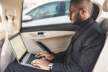 Bir iş kıyafeti adam deri iç ile pahalı bir araba salonda laptop yazmak.