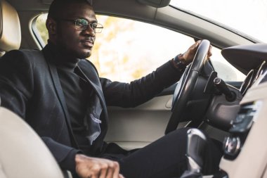 The man presses the buttons in the car. Adjustment of audio volume control.