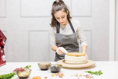 Pastanın üstüne krema sıkan bir pasta torbasıyla pastacı. Ev yapımı hamur işi, kek pişirme....