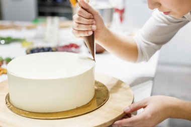 Bir şekerlemeler ahşap bir stand üzerinde beyaz krem bisküvi kek üzerine bir pasta torbası sıvı çikolata sıkır. Ev yapımı pasta kavramı, yemek pastaları.