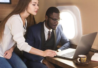 Genç başarılı Afrikalı-Amerikan işadamı gözlük ve çekici bir kadın iş arkadaşı Sarışın özel bir Jet. Hizmet ve uçuş birinci sınıf