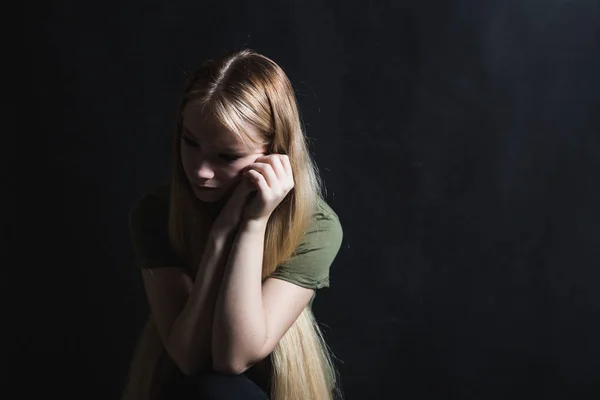 Traurige junge Frau weint vor schwarzem Hintergrund — Stockfoto