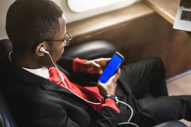 Onun özel iş uçağı sandalyesinde oturup telefonda konuşurken GLASSiES ile genç çekici ve başarılı Afrikalı Amerikan işadamı