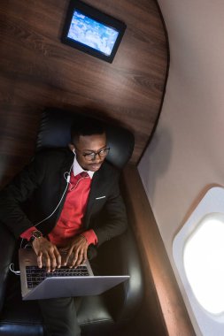 Onun özel jet sandalyede otururken gözlük bir dizüstü bilgisayar üzerinde çalışan çekici ve başarılı Afrikalı Amerikan işadamı