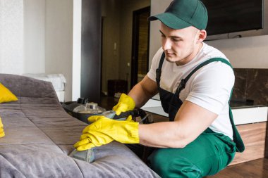 İş sırasında profesyonel ekipmanlarla temizlik hizmeti. Profesyonel mutfak temizliği, kanepe kuru temizleme, pencere ve yer silme. Erkek ve kadın üniformalı, tulumlu ve lastik eldivenli.