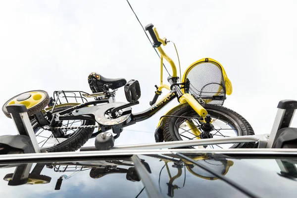 Transporte de bicicleta - uma bicicleta infantil no telhado de um carro contra o céu em uma montagem especial para ciclismo. A decisão de transportar grandes cargas e viajar de carro — Fotografia de Stock