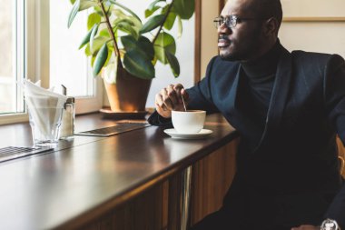 Genç, esmer, yakışıklı iş adamı bir kafede kahve içiyor..