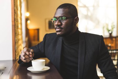 Bir fincan çay ile bir kafede genç yakışıklı Dark-skinned işadamı.