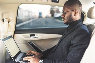 Bir iş kıyafeti adam deri iç ile pahalı bir araba salonda laptop yazmak.