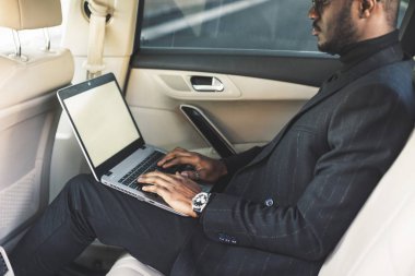 Bir iş kıyafeti adam deri iç ile pahalı bir araba salonda laptop yazmak.
