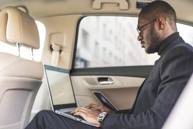 Bir iş kıyafeti adam deri iç ile pahalı bir araba salonda laptop yazmak.