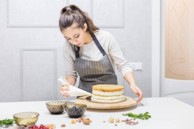 Pastanın üstüne krema sıkan bir pasta torbasıyla pastacı. Ev yapımı hamur işi, kek pişirme....