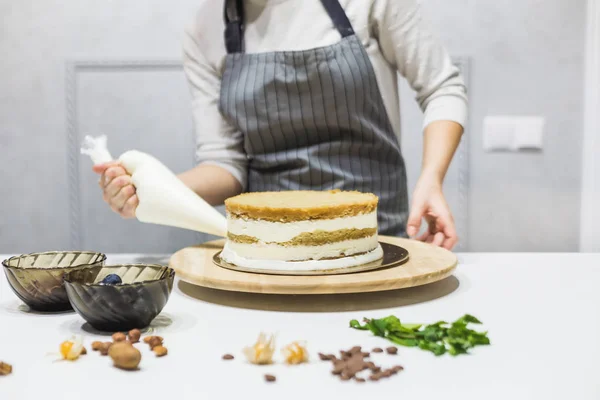 Cukrász cukrászdával, cukrászdával, krémmel a konyhában. A házi sütemény, a sütemények koncepciója. — Stock Fotó