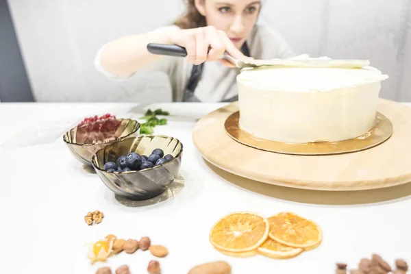 Cukrászda simítja fehér krém egy keksz torta főzés spatula. A házi sütemény, a sütemények koncepciója. — Stock Fotó