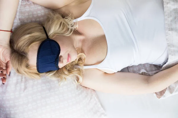 Uma bela mulher loira dormindo em uma máscara de sono em sua cama pela manhã. Vista de cima — Fotografia de Stock