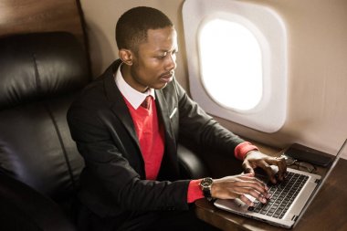 Onun özel jet sandalyede otururken gözlük bir dizüstü bilgisayar üzerinde çalışan çekici ve başarılı Afrikalı Amerikan işadamı