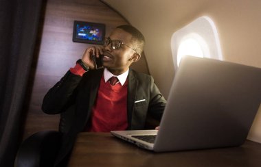 Onun özel jet sandalyede otururken gözlük bir dizüstü bilgisayar üzerinde çalışan çekici ve başarılı Afrikalı Amerikan işadamı