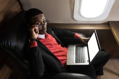 Onun özel jet sandalyede otururken gözlük bir dizüstü bilgisayar üzerinde çalışan çekici ve başarılı Afrikalı Amerikan işadamı