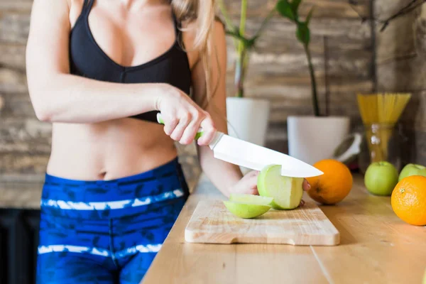 有魅力的女运动员在训练、切水果和做新鲜果汁之前，在厨房准备一份健康的早餐。健康的生活方式、健康和美丽 — 图库照片