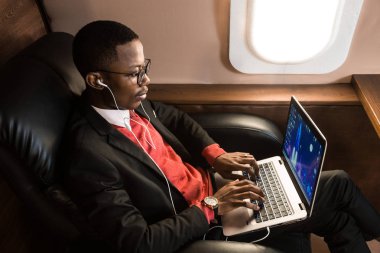 Onun özel jet sandalyede otururken gözlük bir dizüstü bilgisayar üzerinde çalışan çekici ve başarılı Afrikalı Amerikan işadamı