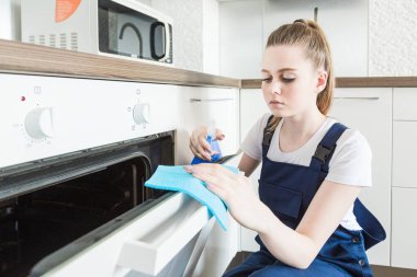 İş sırasında profesyonel ekipmanlarla temizlik hizmeti. Profesyonel mutfak temizliği, kanepe kuru temizleme, pencere ve yer silme. Erkek ve kadın üniformalı, tulumlu ve lastik eldivenli.