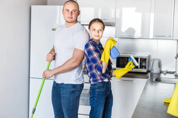 Junges Ehepaar macht Hausreinigung. der Kerl und das Mädchen waschen die Küche mit Wischmopp und Tuch, Teamarbeit, Spaß — Stockfoto
