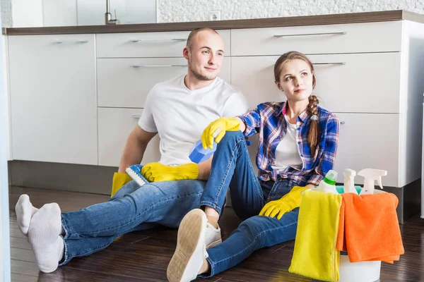 Pareja joven marido y mujer limpian la casa. El chico y la chica lavan la cocina con una fregona y un paño, trabajo en equipo, diversión — Foto de Stock