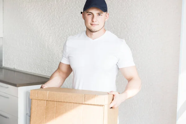 Delivery strong, muscular man loading cardboard boxes for moving to an apartment. professional worker of transportation, male loaders in overalls. free space for text, isolated
