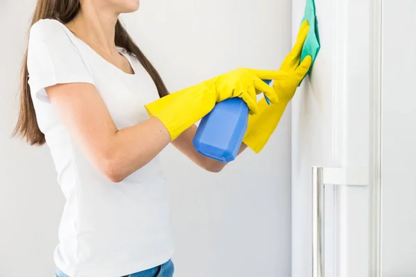 전문적 인 청소 회사에서 일하는 젊은 여자 가집을 청소 한다. 어떤 남자 가 부엌을 세 척합니다 노란색 장갑으로 냉장고를 닦습니다 청소 용품으로 요. — 스톡 사진
